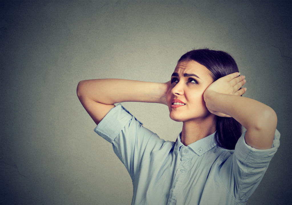 Stressed frustrated woman covering her ears with hands.