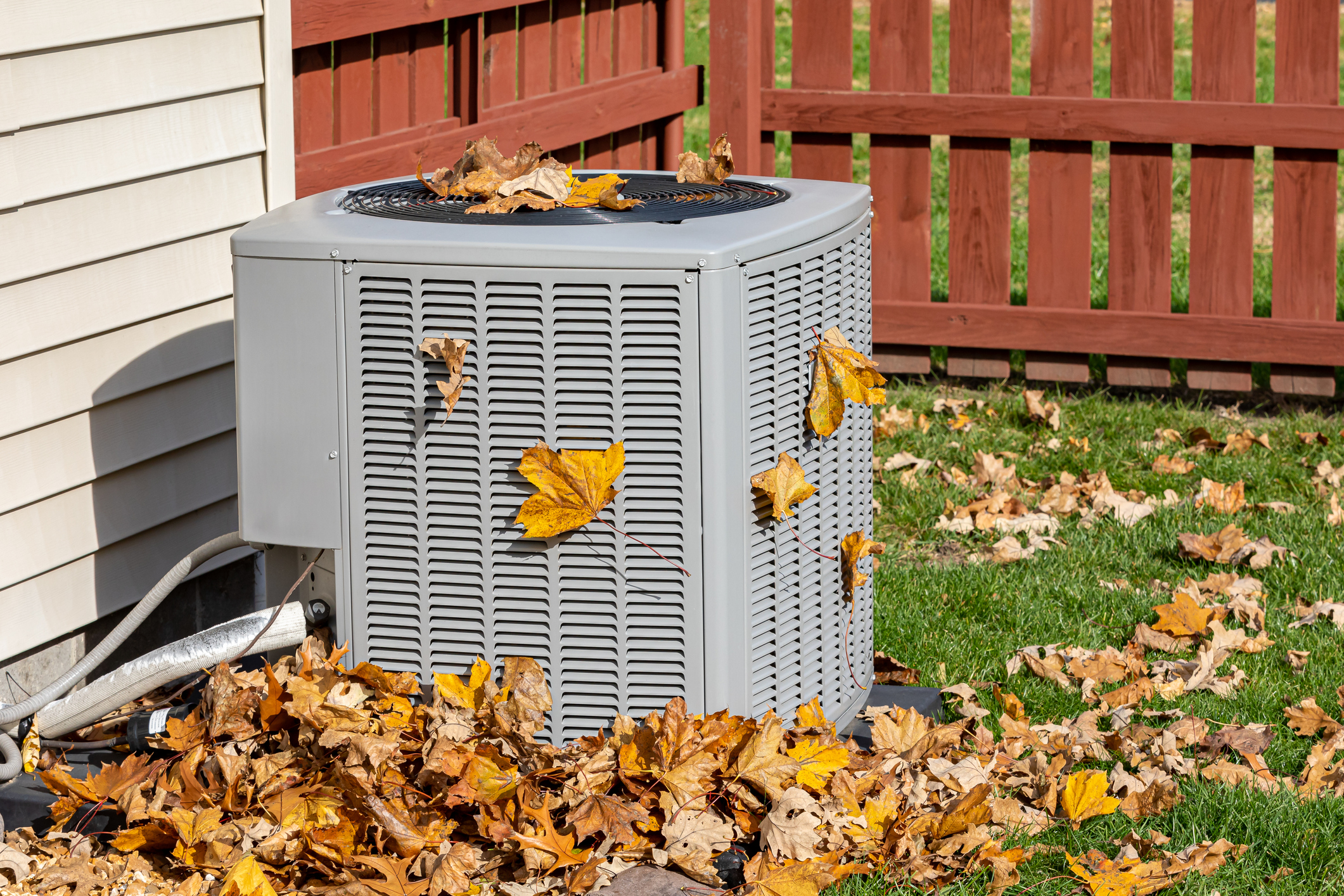 HVAC system outside with fallen leaves around it.